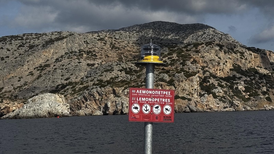 Φωτοσημαντήρας με κόκκινη πινακίδα της ζώνης προστασίας του καταδυτικού πάρκου στις Λεμονόπετρες.