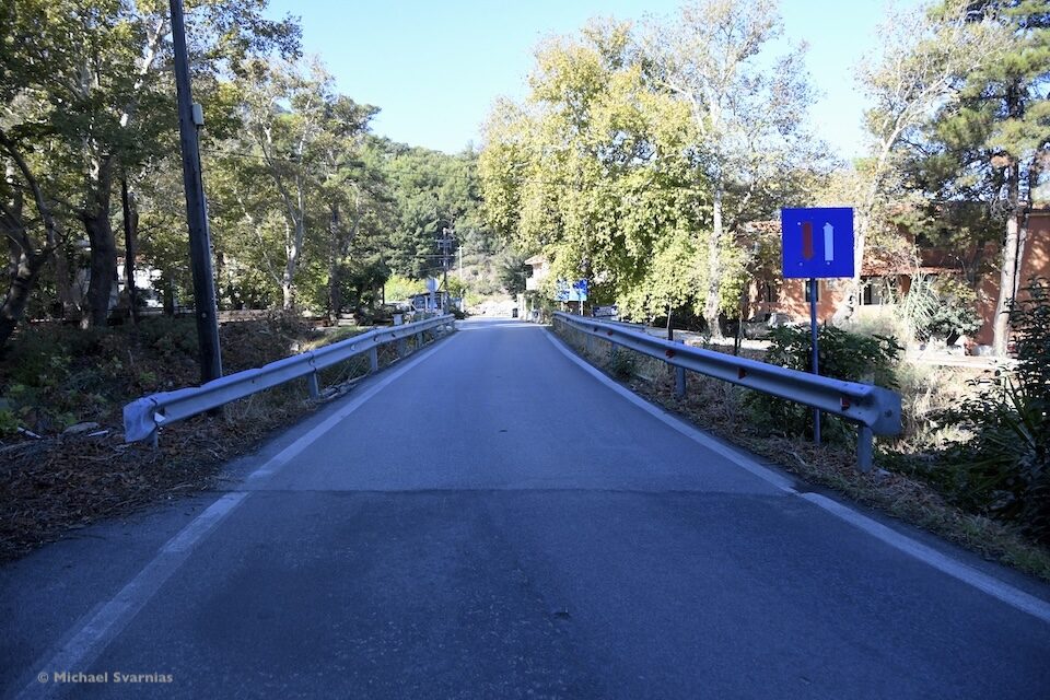 Στενή οδική γέφυρα στον Άγιο Κωνσταντίνο Σάμου, με μεταλλικά στηθαία και πινακίδα προτεραιότητας.