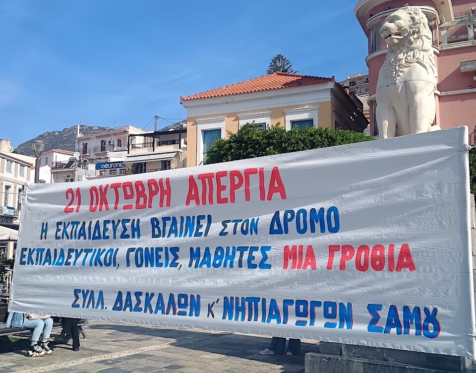 Πανό του Συλλόγου Δασκάλων και Νηπιαγωγών Σάμου για την απεργία της 21ης Οκτωβρίου, μπροστά στο άγαλμα του λιονταριού στην πλατεία Πυθαγόρα.