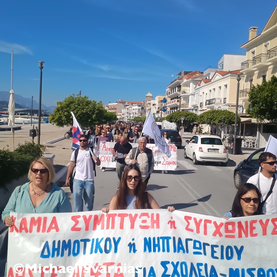 Διαδηλωτές με πανό κατά των συγχωνεύσεων σχολικών τμημάτων και σημαίες στην παραλιακή λεωφόρο Θεμιστοκλή Σοφούλη στη Σάμο.